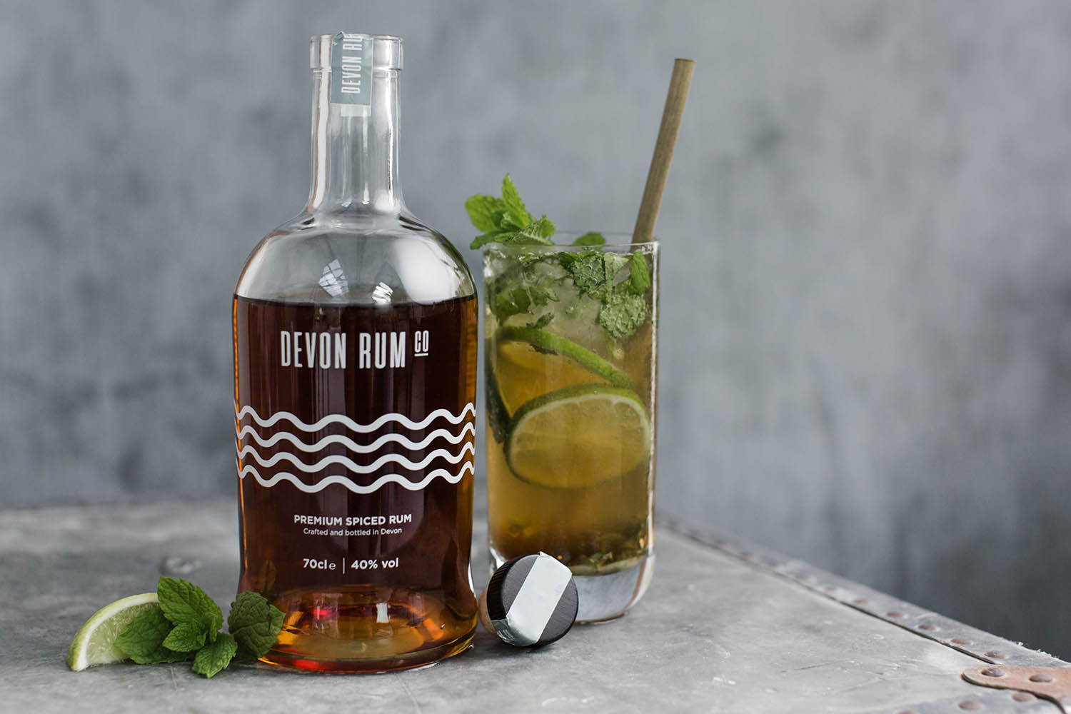 OPen bottle of Devon Rum with a mixed mojito cocktail next to it