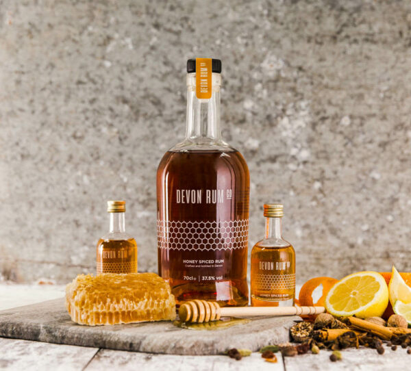 Bottle of Honey Spiced Rum surrounded by citrus fruit and honeycomb