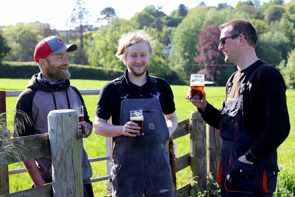 Three Exmoor Ales brewers in a field drinking beer