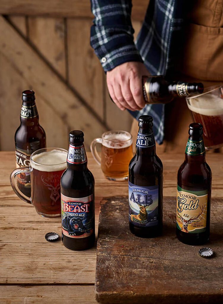 Bottles of ales on a table with ands filling a tankard with Exmoor Stag