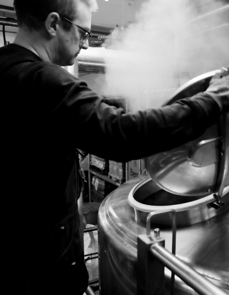 Head brewer opening a brew vat with steam coming out